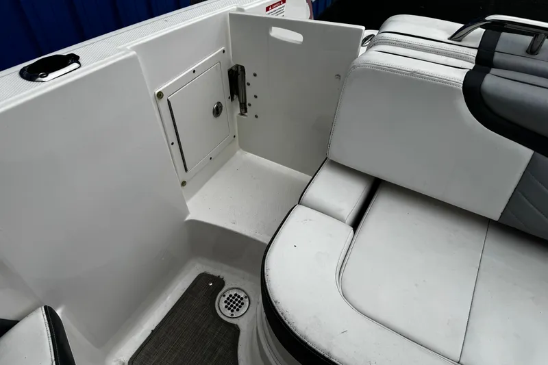 Slide: The Image of 2020 Chaparral 277 SSX boat interior with white seating and storage compartment. - 17