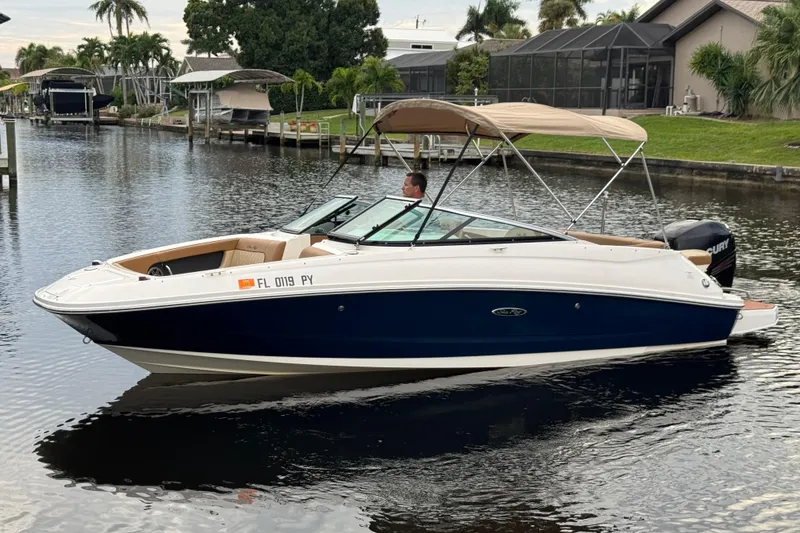 Slide: The Image of 2015 Sea Ray 220 Sundeck Outboard boat on a calm canal, featuring a sleek design. - 11