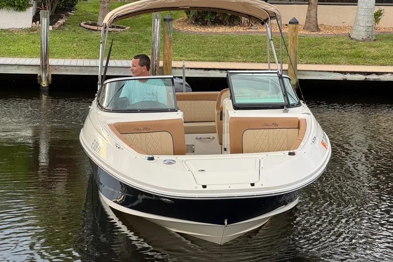Slide: The Image of 2015 Sea Ray 220 Sundeck Outboard boat on calm water near a dock. - 13