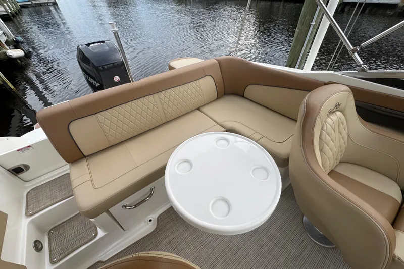 Slide: The Image of 2015 Sea Ray 220 Sundeck Outboard interior with tan seating and round table. - 27
