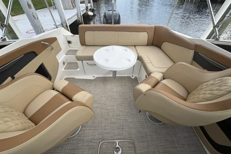 Slide: The Image of 2015 Sea Ray 220 Sundeck Outboard interior with beige seating and round table. - 28
