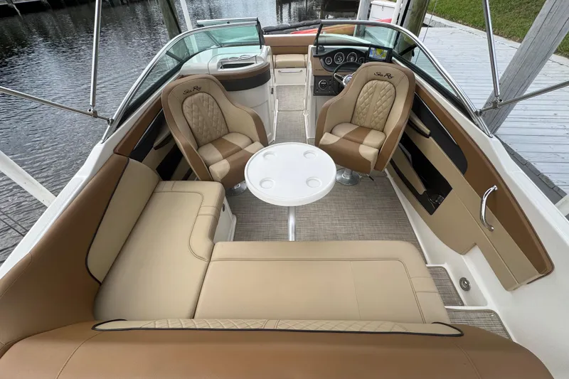 Slide: The Image of 2015 Sea Ray 220 Sundeck Outboard interior with tan seating and round table. - 29
