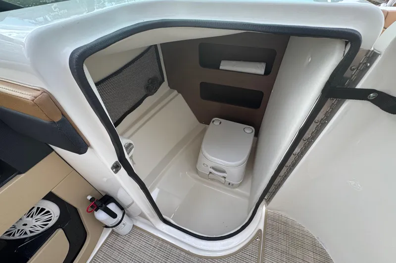Slide: The Image of 2015 Sea Ray 220 Sundeck Outboard boat interior with compact toilet and storage. - 31