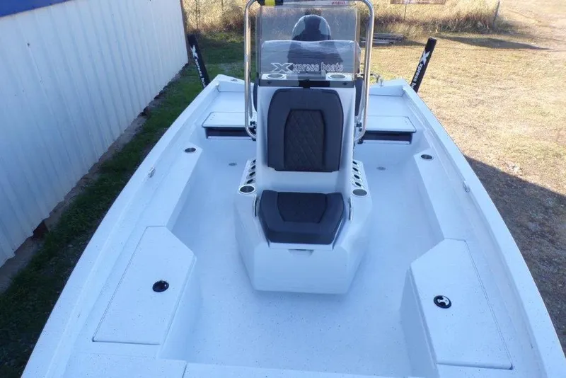 Slide: The Image of 2026 Xpress H20B Bay boat interior with seating and console, parked outdoors. - 8