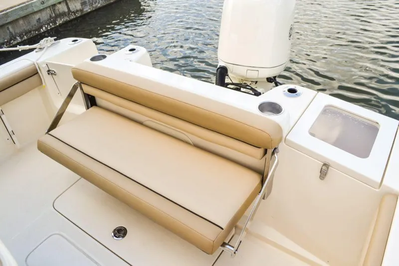 Slide: The Image of Manufacturer Provided Image: 2025 Scout 215 XSF boat with tan seating and outboard motor by the water. - 15