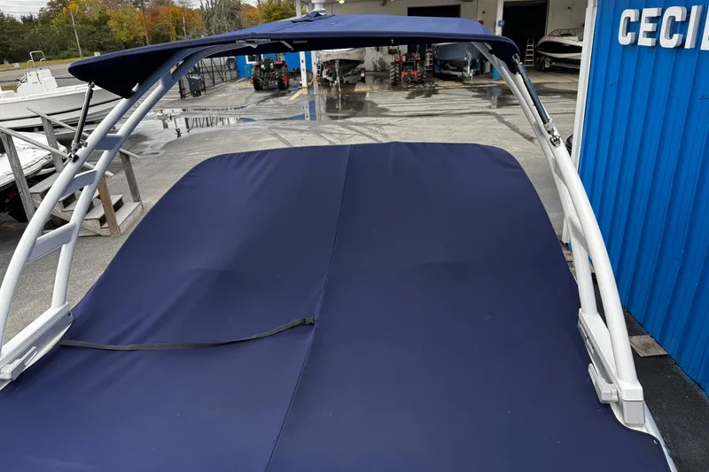 Slide: The Image of 2023 Chaparral 21 SSi OB boat with blue cover and metal frame in a marina. - 4