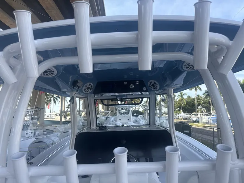 Slide: The Image of 2026 Sportsman Open 352 Center Console boat with rod holders and speakers, docked under a bridge. - 20