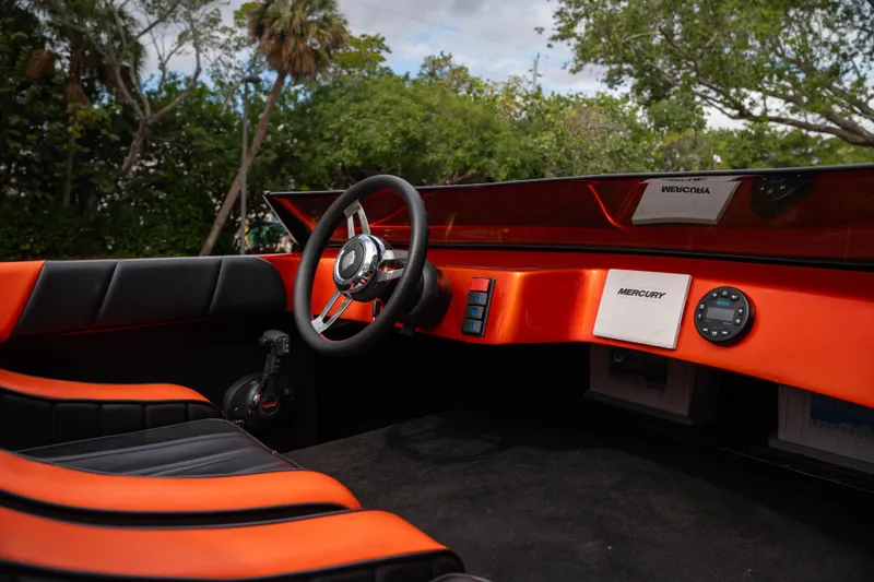 Slide: The Image of 1984 Sleekcraft Aristocrat 20 boat interior with orange and black design, featuring a steering wheel. - 13