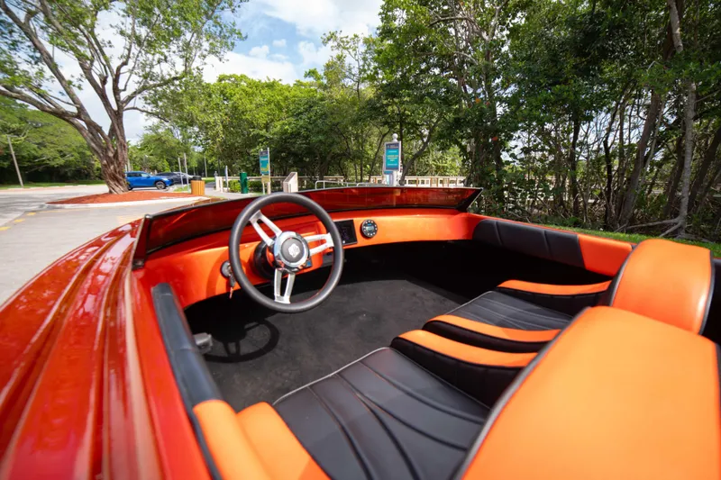 Slide: The Image of 1984 Sleekcraft Aristocrat 20 boat interior with orange and black seating, parked near trees. - 15