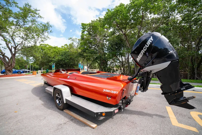 Slide: The Image of 1984 Sleekcraft Aristocrat 20 boat with Mercury engine on trailer, parked near trees. - 2