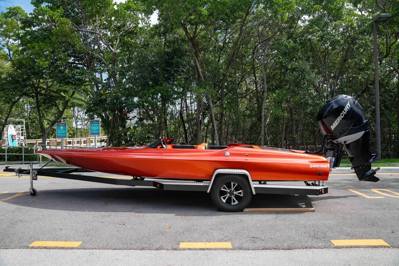 Slide: The Image of 1984 Sleekcraft Aristocrat 20 boat on trailer, vibrant orange, parked outdoors. - 20