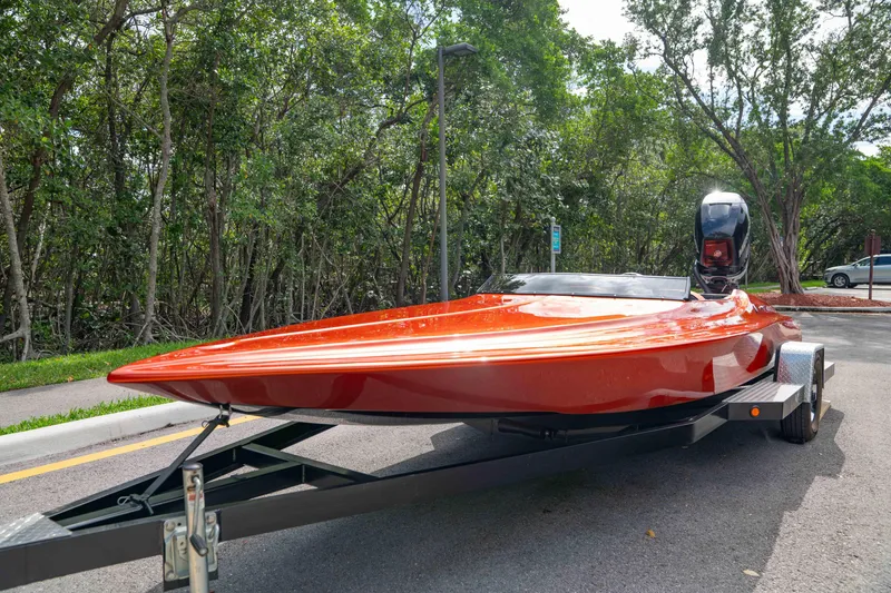Slide: The Image of 1984 Sleekcraft Aristocrat 20 boat on trailer, vibrant orange finish, parked near lush greenery. - 23
