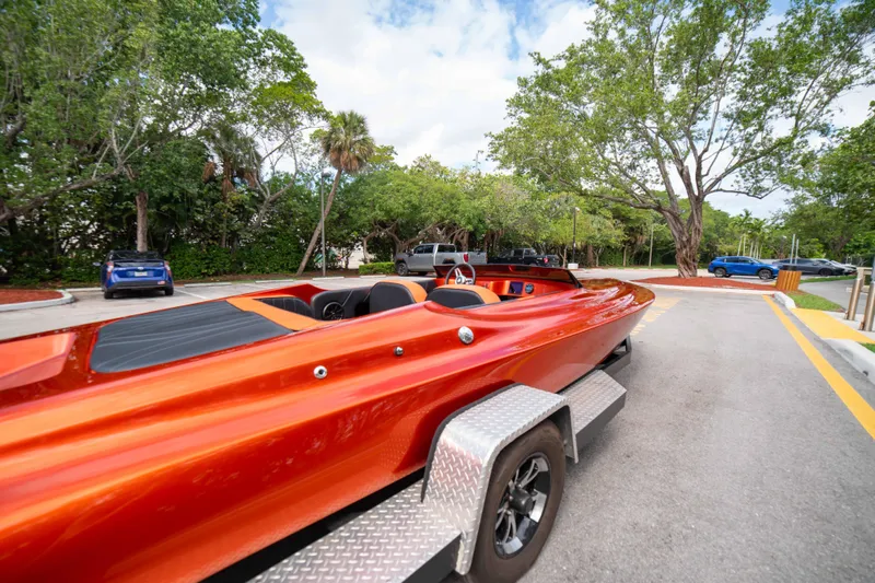 Slide: The Image of 1984 Sleekcraft Aristocrat 20 boat on trailer, vibrant orange, parked near trees. - 4
