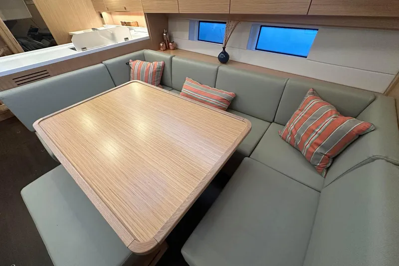 Slide: The Image of Modern Bavaria C45 yacht interior with cozy dining area, featuring cushioned seating and wooden table. - 24