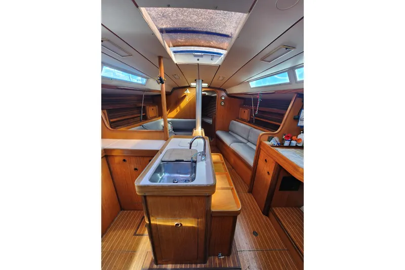 Slide: The Image of Interior of 1988 Beneteau First 405 sailboat, featuring wood finishes and a compact kitchen area. - 10