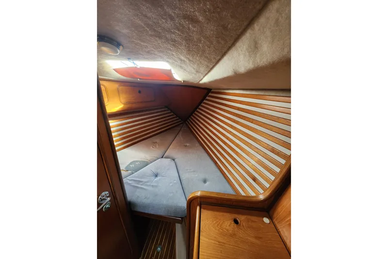 Slide: The Image of Cozy cabin interior of 1988 Beneteau First 405 sailboat with wooden accents and cushioned berth. - 34