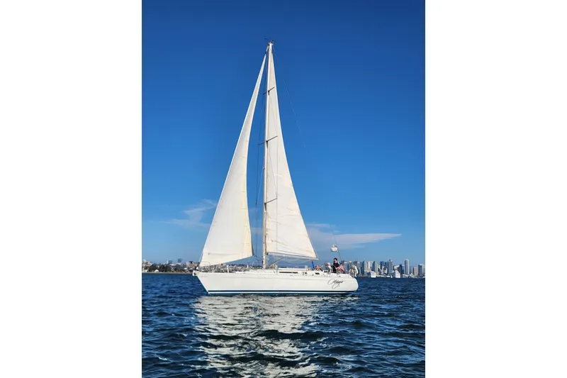 Slide: The Image of 1988 Beneteau First 405 sailboat on open water with city skyline in background. - 43