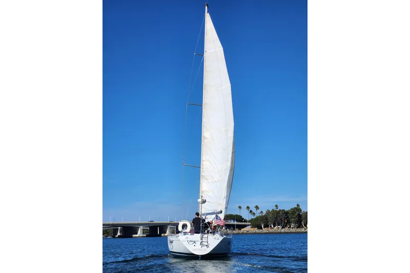 Slide: The Image of 1988 Beneteau First 405 sailboat on open water under clear blue sky. - 50