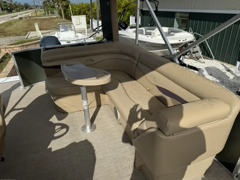Slide: The Image of 2018 Bennington 21 SLX pontoon boat with beige seating and small table on deck. - 10