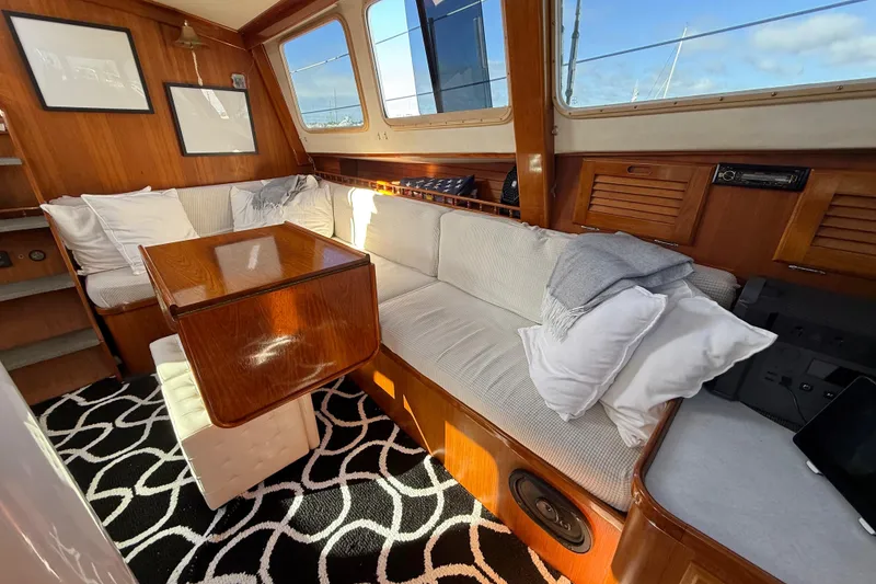 Slide: The Image of Cozy 1973 CAL 246 yacht interior with wooden table, cushioned seating, and nautical decor. - 21