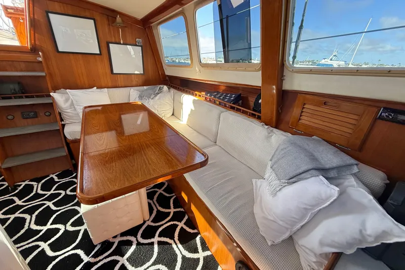 Slide: The Image of Interior of a 1973 CAL 246 boat with wooden table, cushioned seating, and nautical decor. - 22