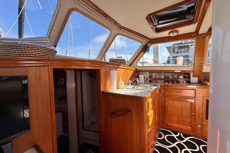 Slide: The Image of Interior of 1973 CAL 246 sailboat with wooden cabinetry and modern kitchen amenities. - 27