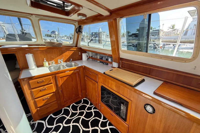 Slide: The Image of 1973 CAL 246 yacht interior with wooden cabinetry, sink, and marina view. - 30
