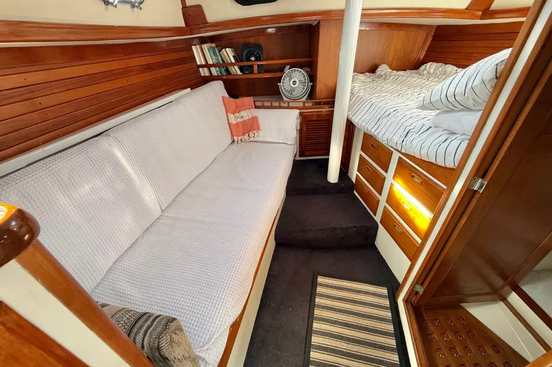 Slide: The Image of 1973 CAL 246 yacht interior with cozy seating, wooden cabinetry, and a striped bed. - 60