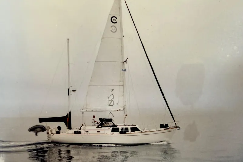 Slide: The Image of 1973 CAL 246 sailboat on calm water, featuring white sails and sleek design. - 65