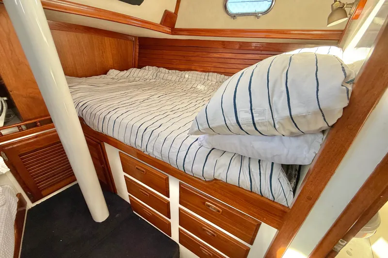 Slide: The Image of Cozy cabin interior of 1973 CAL 246 sailboat with striped bedding and wooden storage drawers. - 74