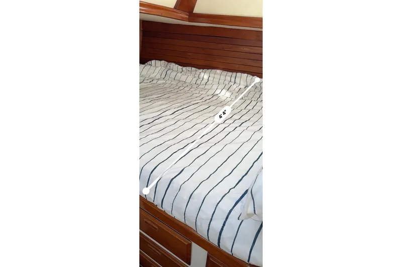 Slide: The Image of Striped bedding in a 1973 CAL 246 boat cabin with wooden interior. - 75