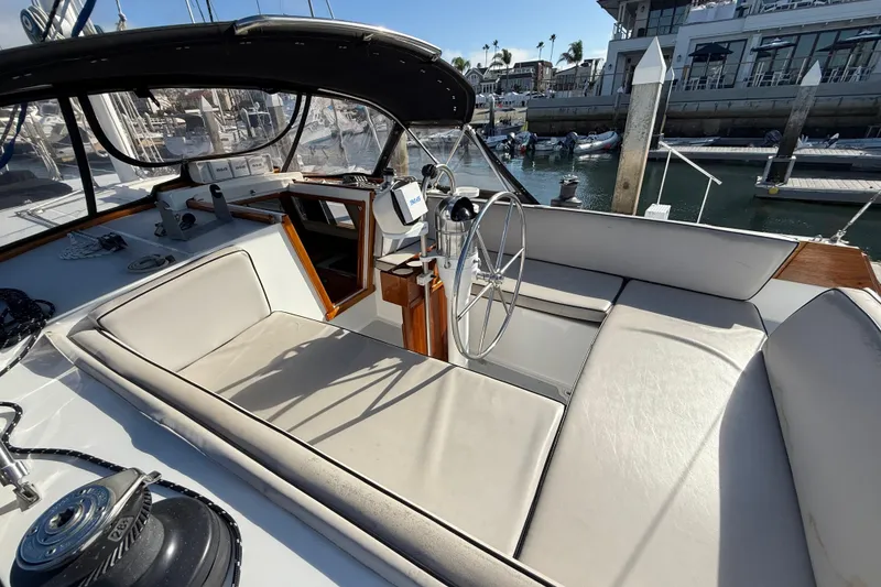 Slide: The Image of Cockpit of a 1973 CAL 246 sailboat with steering wheel and seating, docked at marina. - 8