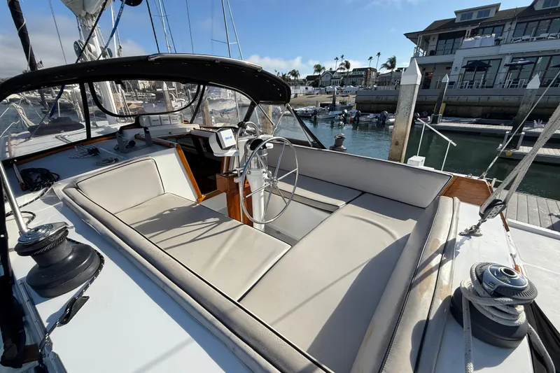 Slide: The Image of 1973 CAL 246 sailboat cockpit with steering wheel, docked at marina under clear sky. - 9