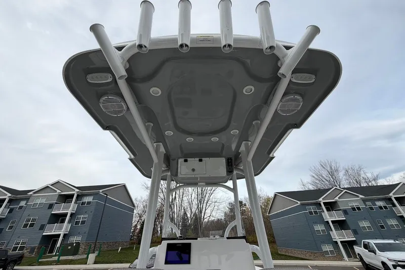 Slide: The Image of 2023 Sea Pro 219 Center Console boat with T-top and rod holders, parked near residential buildings. - 46
