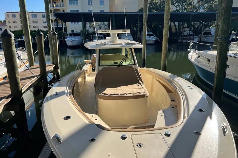 Slide: The Image of 2024 Scout 425 LXF boat docked in marina, front view with covered seating area. - 16