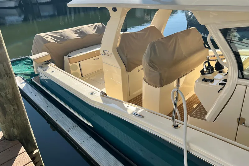 Slide: The Image of 2024 Scout 425 LXF boat docked, featuring covered seats and sleek design. - 17