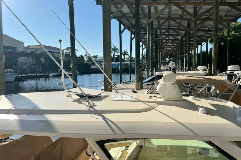 Slide: The Image of 2024 Scout 425 LXF boat docked under covered marina with clear blue sky. - 18