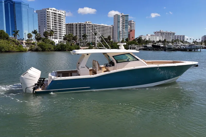 Slide: The Image of 2024 Scout 425 LXF boat cruising in a scenic urban waterfront setting. - 2