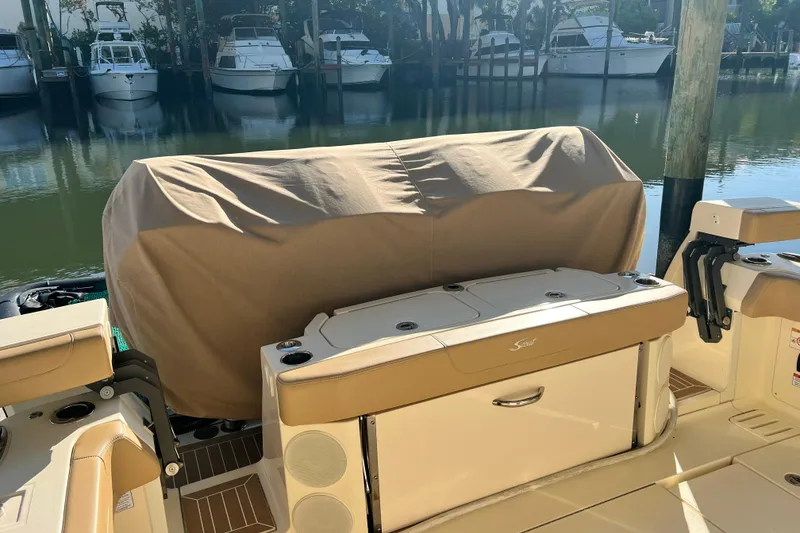 Slide: The Image of 2024 Scout 425 LXF boat interior with covered seating, docked near other boats. - 22