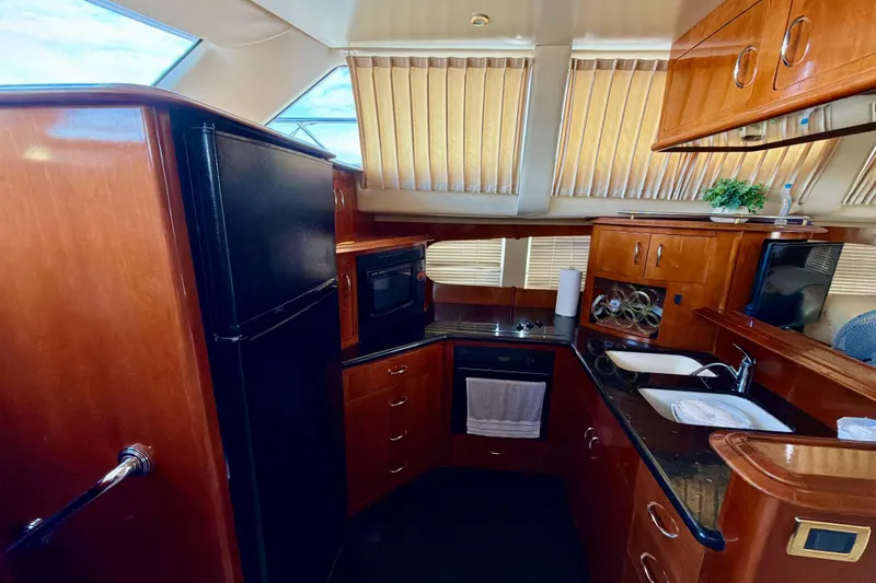Slide: The Image of 2003 Carver 564 Cockpit Motor Yacht kitchen with wood cabinetry and modern appliances. - 23