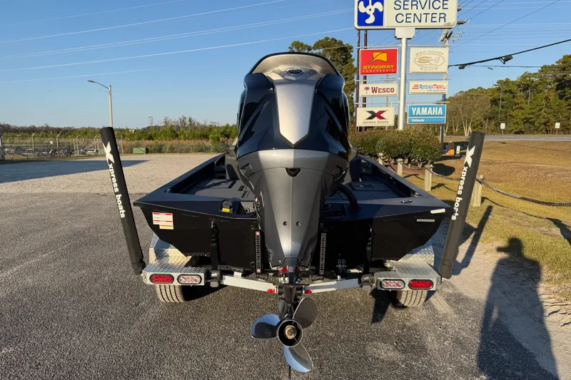 Slide: The Image of 2025 Xpress X21 Pro boat at service center, rear view with motor and trailer. - 8