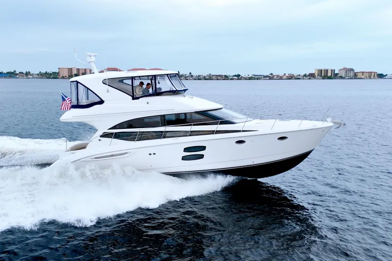 Slide: The Image of 2013 Meridian 441 Sedan yacht cruising on open water with cityscape in background. - 6