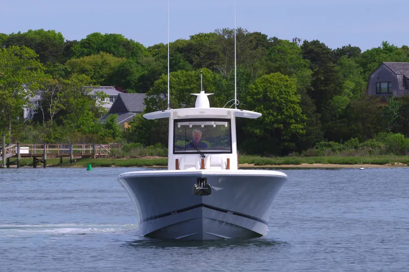 Slide: The Image of 2025 Regulator 35 boat cruising on a calm lake with lush green shoreline. - 3