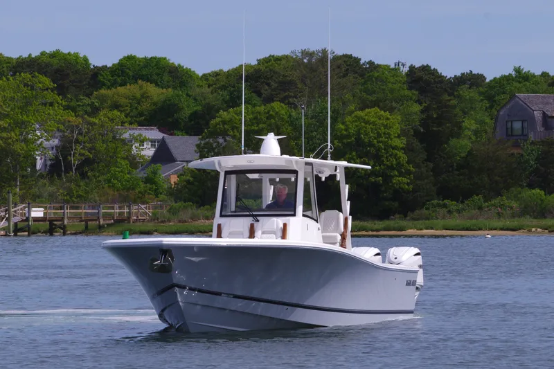 Slide: The Image of 2025 Regulator 35 boat cruising on a calm lake near a wooded shoreline. - 4