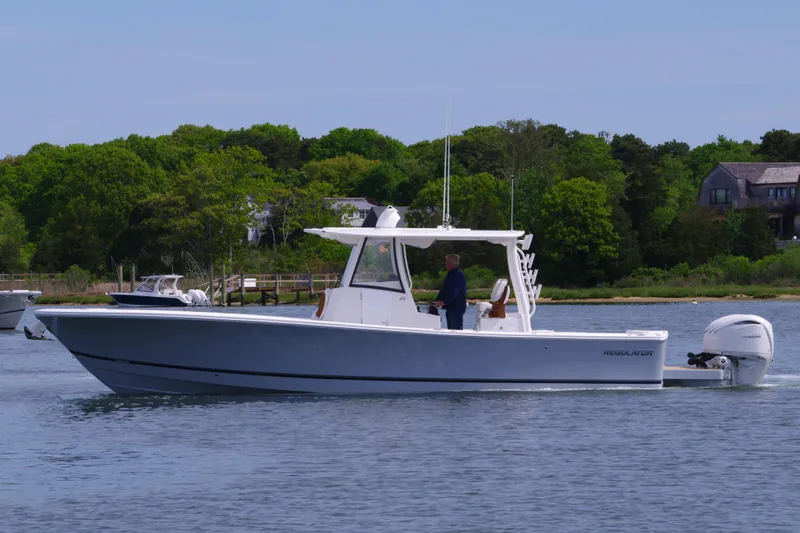 Slide: The Image of 2025 Regulator 35 boat cruising on a calm lake with lush green trees in the background. - 6