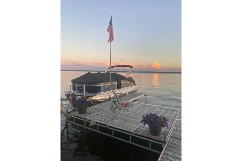 Slide: The Image of 2022 Barletta Cabrio 22UC pontoon boat docked at sunset with American flag. - 3