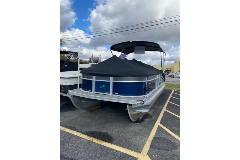 Slide: The Image of 2022 Barletta Cabrio 22UC pontoon boat with cover, parked outdoors under cloudy sky. - 7