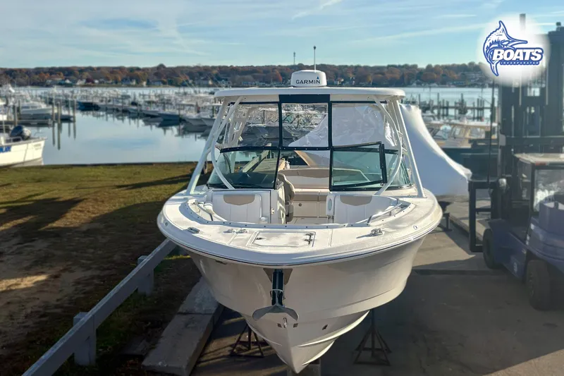 Slide: The Image of 2019 Robalo R317 Dual Console boat docked at a marina with scenic background. - 2