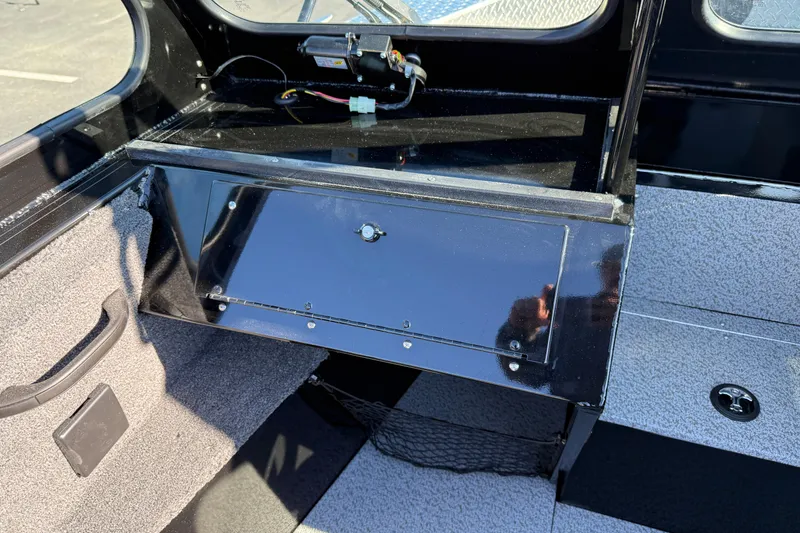 Slide: The Image of Interior of 2026 Crestliner 2050 Commander Elite boat, featuring storage compartment and carpeted flooring. - 12