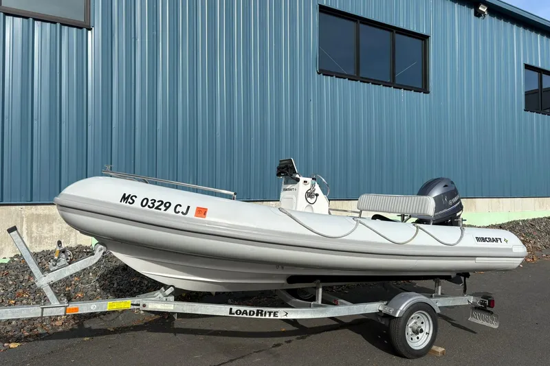 The Image of 2024 Ribcraft 4.8T inflatable boat on trailer, parked by blue building. - 0